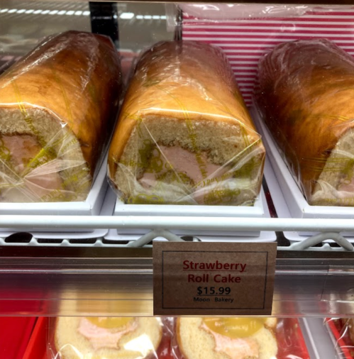 Three wrapped strawberry roll cakes displayed in a bakery case, with a price tag of $15.99.