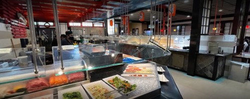 A spacious restaurant buffet with various food stations, including sushi, salads, and fresh ingredients.