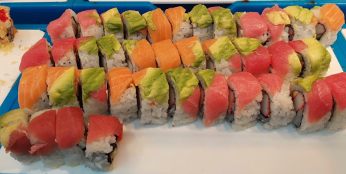 A colorful assortment of sushi rolls arranged neatly on a blue tray, featuring various fish and avocado toppings.