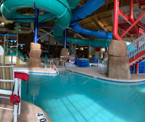 Indoor water park featuring colorful water slides, a pool, and lounge chairs.