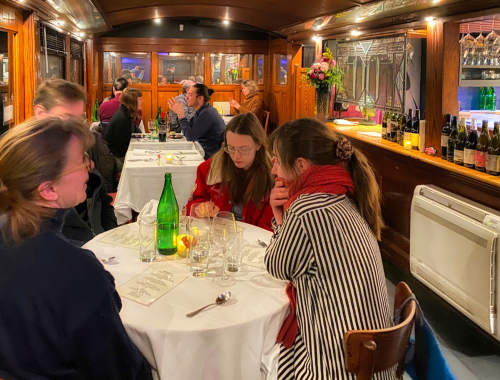 A cozy restaurant scene with diners at tables, warm lighting, and wooden decor, creating an intimate atmosphere.