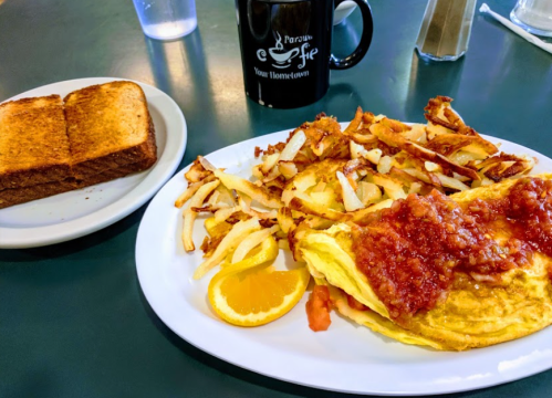 A plate with an omelet topped with salsa, hash browns, and an orange slice, alongside a slice of toast and a coffee mug.