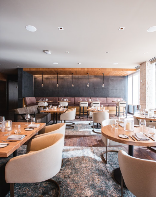 Modern restaurant interior with wooden tables, plush seating, and elegant lighting. Cozy and inviting atmosphere.