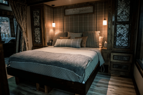 Cozy bedroom featuring a large bed with patterned bedding, wooden accents, and soft lighting.