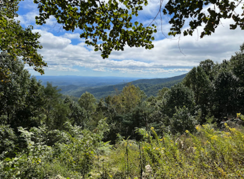A scenic view of rolling mountains and lush greenery under a partly cloudy sky.