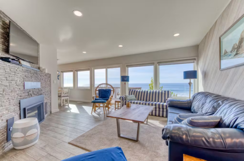 Cozy living room with ocean views, featuring a sofa, armchair, coffee table, and large windows.