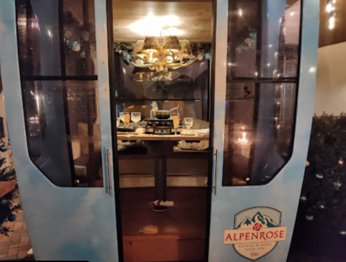 A cozy dining gondola with a table set for two, surrounded by festive decorations and soft lighting.