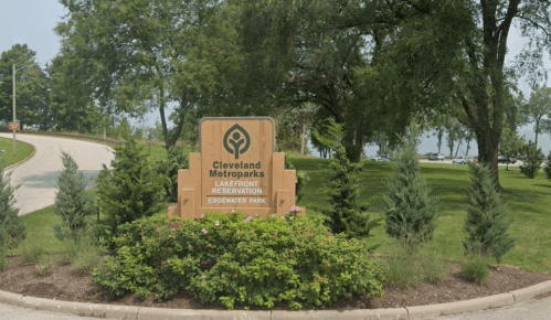 Sign for Cleveland Metroparks Lakefront Reservation at Edgewater Park, surrounded by greenery and trees.