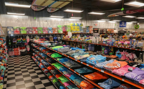 A colorful retail store interior filled with shelves of t-shirts, toys, and various merchandise.