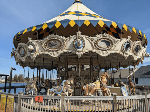 A vintage carousel with ornate decorations and various animal figures, set against a clear blue sky.