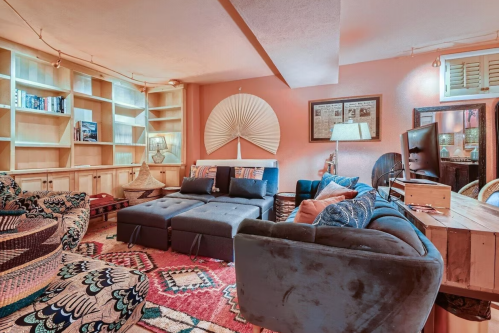 Cozy basement living area with colorful rugs, plush seating, and built-in shelves, creating a warm, inviting atmosphere.