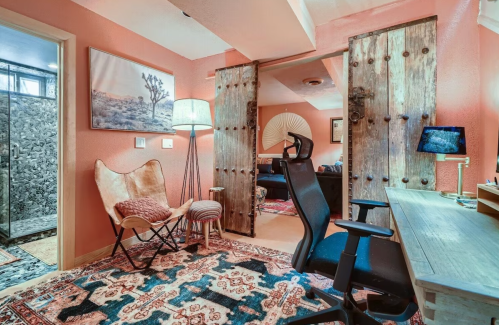 Cozy room with rustic decor, featuring a desk, chair, butterfly chair, and sliding wooden doors.
