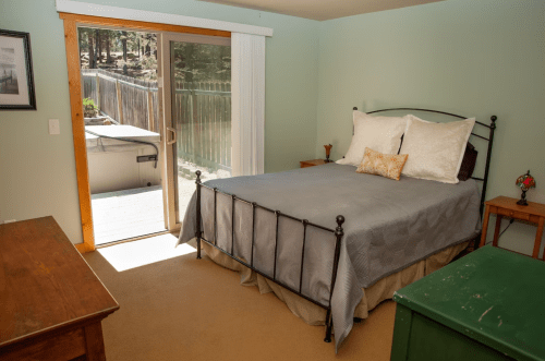Cozy bedroom with a metal bed, light green walls, and a sliding door leading to a deck.