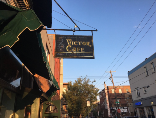 Sign for Victor Cafe, featuring "Music Lovers' Rendezvous," with a clear blue sky in the background.