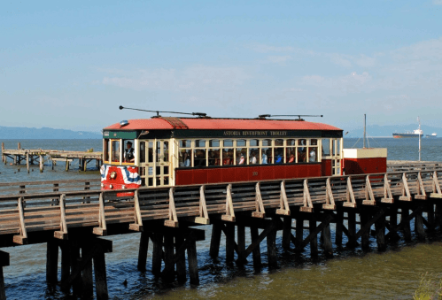 A vintage trolley on a wooden pier, with passengers enjoying a scenic ride over the water.
