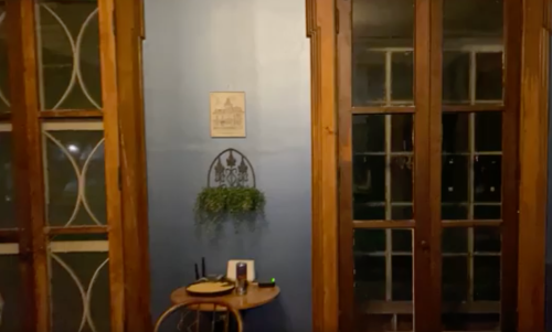 A cozy room with wooden doors, a blue wall, and a small table with a plant and utensils.