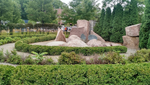 A landscaped garden featuring large rocks, trimmed hedges, and greenery, creating a serene outdoor space.
