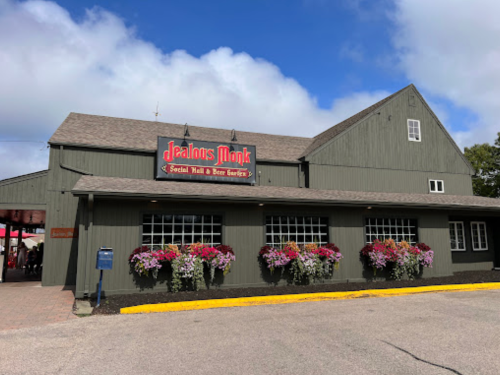 Exterior of Deacon's Monk, a social hall and beer garden, featuring flower boxes and a rustic building design.