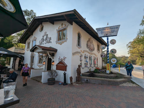 A charming, decorated restaurant building with outdoor seating and a sign, set in a scenic area.