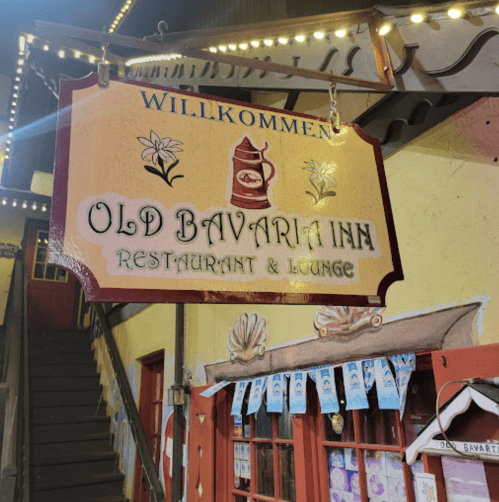 Sign for "Old Bavaria Inn Restaurant & Lounge" with decorative elements, illuminated at night.