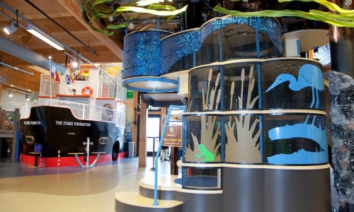 Interior view of an educational space featuring colorful displays, aquatic themes, and a large ship in the background.