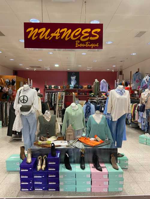 Display of clothing and accessories at Nuances Boutique, featuring mannequins and various apparel in a retail setting.