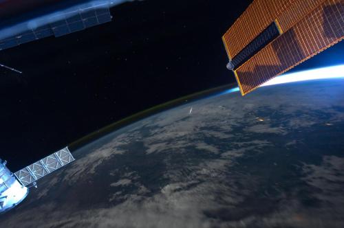 View of Earth from space, featuring the curvature of the planet and solar panels of a spacecraft against a starry background.