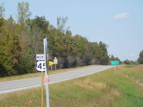 A highway sign indicating North 45, with a clear road and trees lining the side under a blue sky.