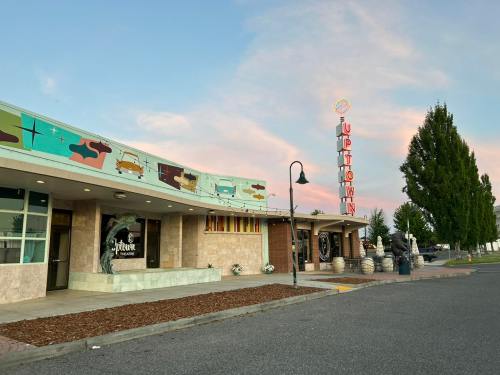 A retro-style diner with colorful murals and a neon sign, set against a pastel sky and lined with trees.