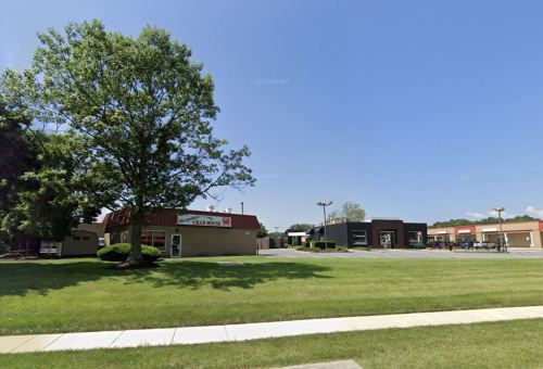 A sunny day view of a commercial area featuring a building with a red roof and nearby modern structures.