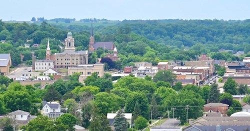 A scenic view of a small town with historic buildings, churches, and lush green hills in the background.
