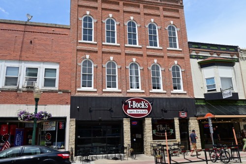 Exterior of T-Bock's Sports Bar & Grill, a brick building with large windows, located in a downtown area.