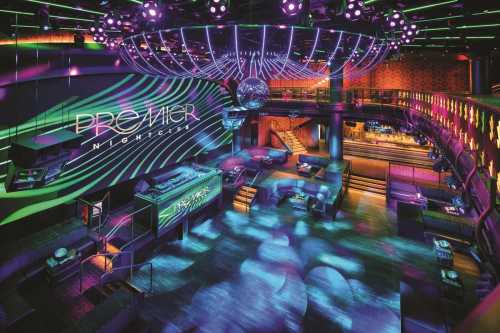 A vibrant nightclub interior with colorful lights, a disco ball, and a spacious dance floor.