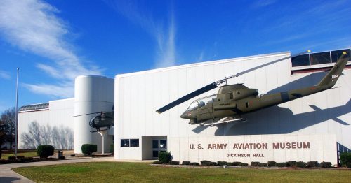 Exterior of the U.S. Army Aviation Museum, featuring helicopters mounted on the building and a clear blue sky.
