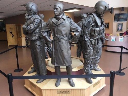 A bronze statue depicting four military figures in various uniforms, standing on a circular base in a public space.