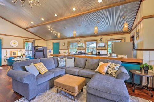 Cozy living room with a large gray sectional sofa, coffee table, and open kitchen area featuring rustic decor.