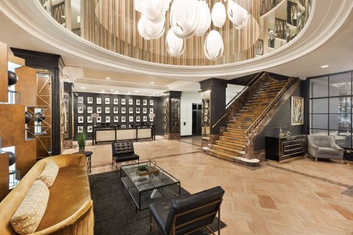 Elegant hotel lobby featuring a grand staircase, modern furniture, and stylish lighting fixtures.