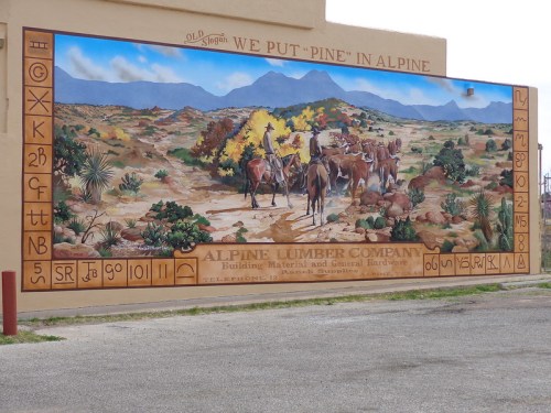 Mural depicting a cowboy scene with horses and mountains, featuring text about Alpine Lumber Company.