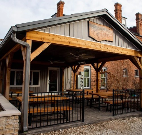 Outdoor seating area of a rustic restaurant with wooden tables and a covered porch.