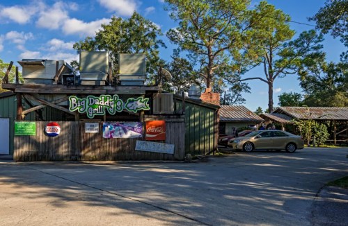 Exterior of Big Daddy's Grill, featuring a rustic building with signage and a car parked nearby under a blue sky.