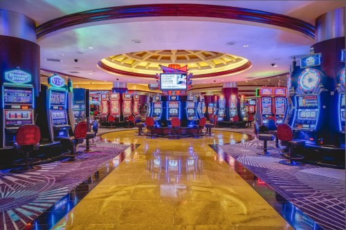 A vibrant casino interior featuring rows of colorful slot machines and illuminated decor.