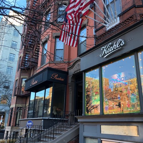A street view of two storefronts, one for Kiehl's and another labeled "Paradise," with an American flag hanging above.