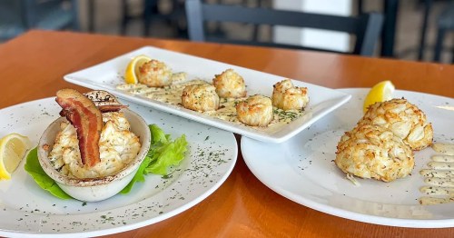 Three plates of crab cakes: one with bacon, two with lemon wedges, garnished with herbs and served on white dishes.