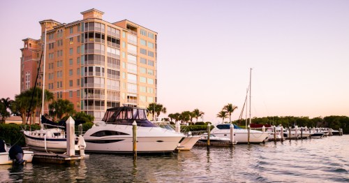 White motorboats and sailboats docked at a marina in Naples, Florida.