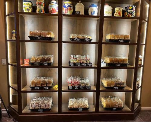 A wooden display shelf filled with various jars and packaged snacks, labeled with prices.