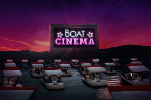 A vibrant sunset scene featuring boats arranged in water, with a large screen displaying "BOAT CINEMA."