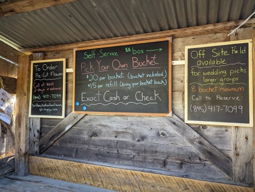 A chalkboard sign detailing self-service flower picking prices and contact information for reservations.