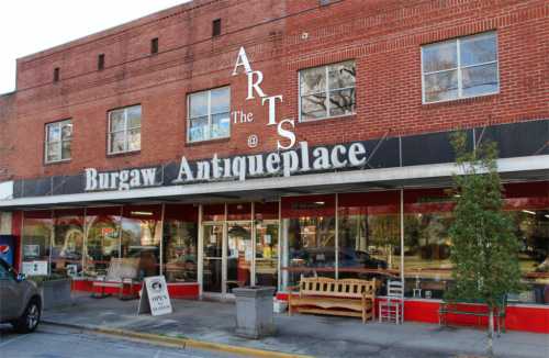 Exterior of Burgaw Antiqueplace featuring large windows and a sign that reads "The Arts @ Burgaw Antiqueplace."