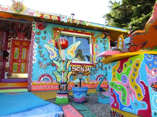 Colorful, whimsical house decorated with butterflies and vibrant patterns, featuring a bright blue exterior and artistic details.