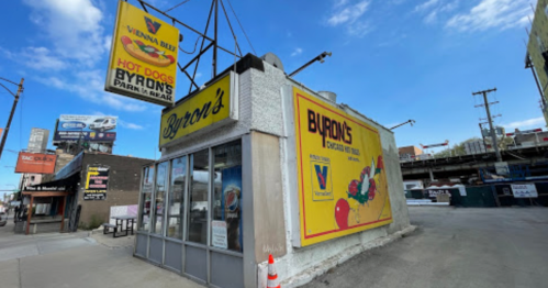 A corner building with a sign for "Byron's" and a colorful advertisement, set against a blue sky.